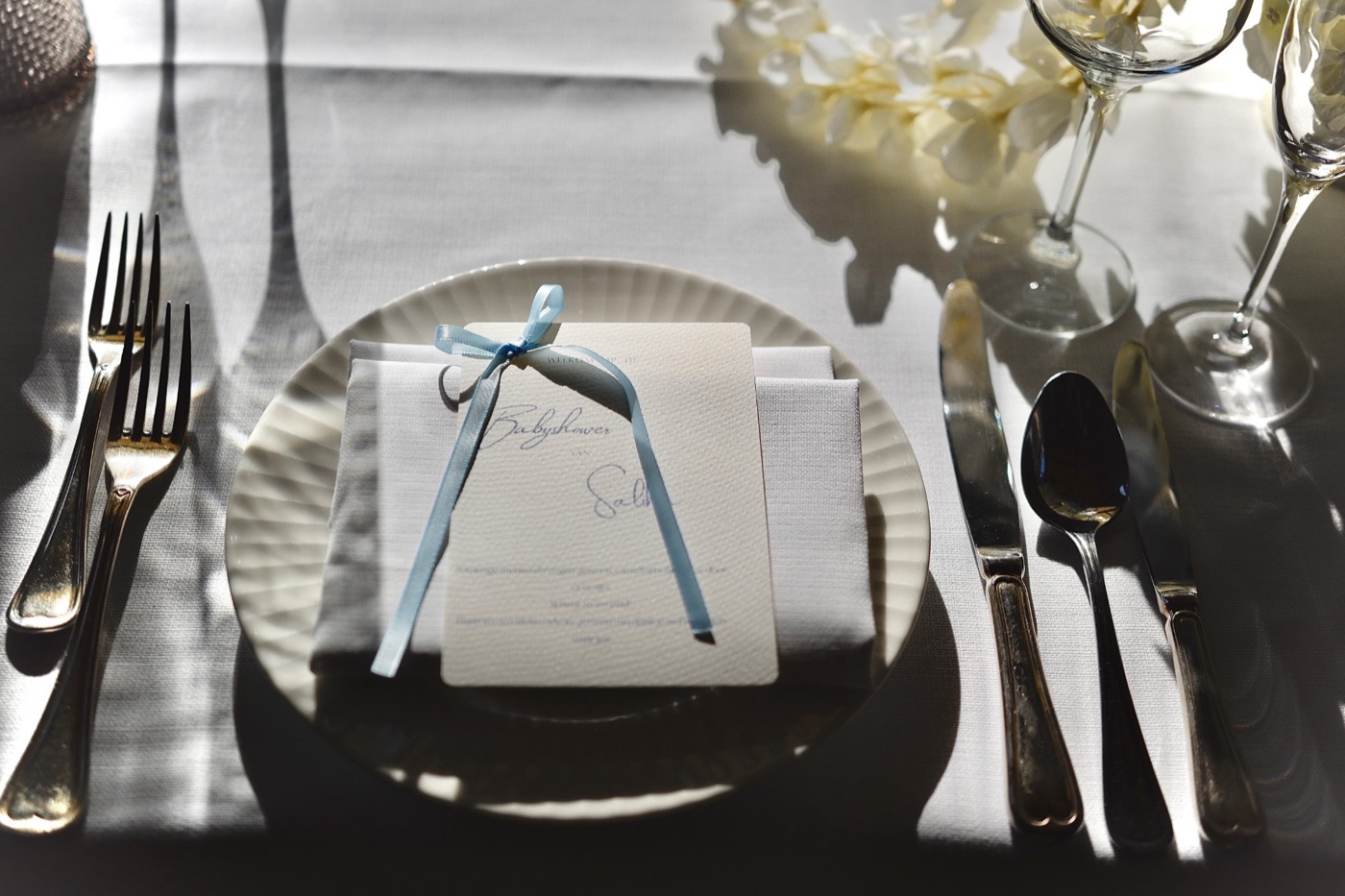 Bord met servet en babyshower-kaart met lichtblauw lint op een gedekte tafel