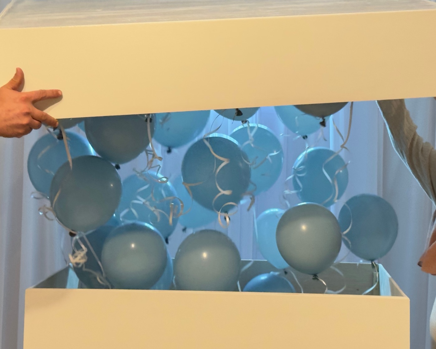 Witte box die wordt geopend met blauwe ballonnen erin